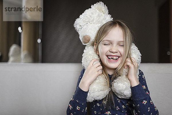 Porträt eines lachenden kleinen Mädchens mit Zahnlücke  das einen weißen Teddybär hält