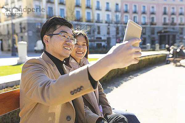 Spanien  Madrid  junges Paar  das sich auf einer Bank ausruht und ein Selfie in der Stadt macht