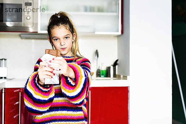 Porträt eines Mädchens in gestreiftem Pullover in der heimischen Küche beim Schokoladenessen