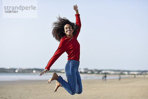 Unbeschwerte junge Frau springt am Strand