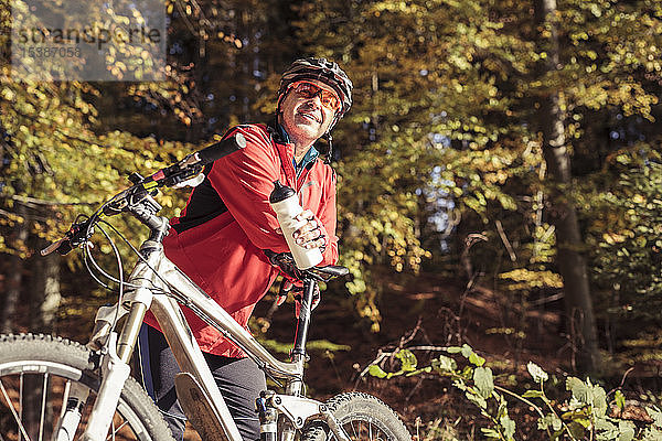 Mann mit Mountainbike bei einer Pause im Wald