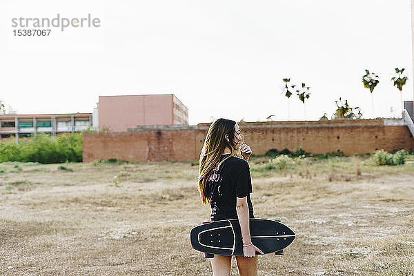 Spanien  Teenagerin hält Skateboard im Freien