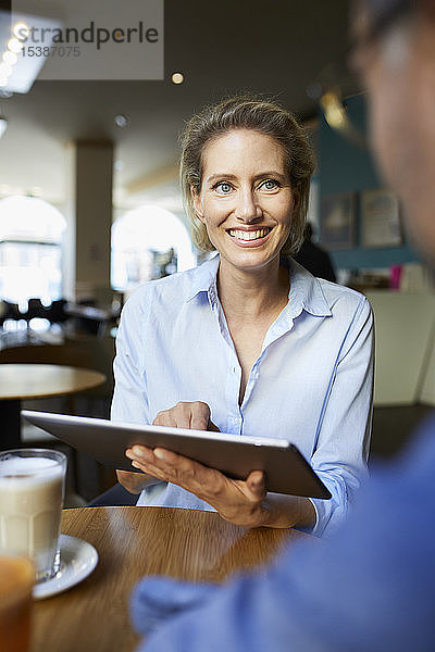 Lächelnde Frau und Mann mit Tablette in einem Cafe