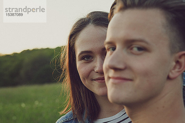 Porträt einer glücklichen Teenagerin  die sich hinter ihrem Freund versteckt