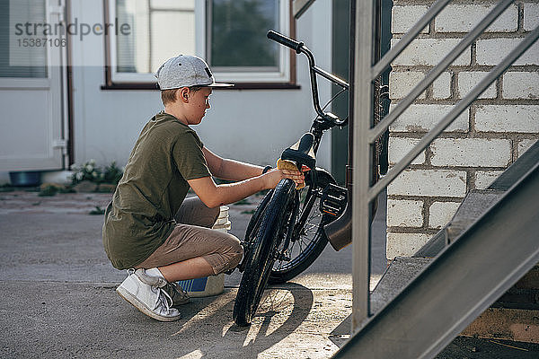 Junge reinigt bmx Fahrrad auf dem Hof
