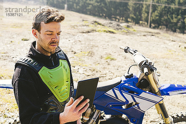 Portrait eines Motocross-Fahrers beim Blick auf das Tablet