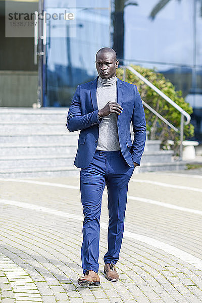 Porträt eines modischen Geschäftsmannes in blauem Anzug und grauem Rollkragenpullover