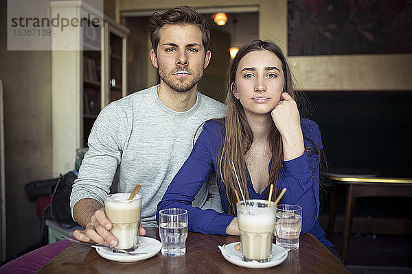 Porträt eines jungen Paares in einem Cafe mit Milchschaum auf den Lippen