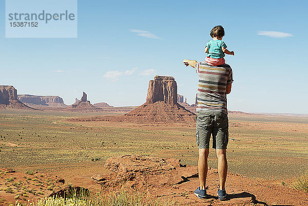 USA  Utah  Monument Valley  Vater reist mit Baby  Mädchen auf den Schultern und zeigt auf die Landschaft des Monument Valley