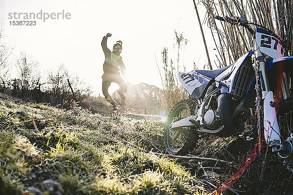 Motocross-Pilot jubelt bei Sonnenuntergang auf der Rennstrecke