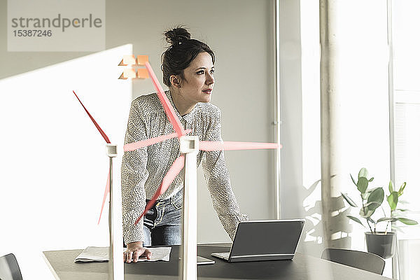 Geschäftsfrau mit Windradmodellen und Laptop auf dem Schreibtisch im Büro