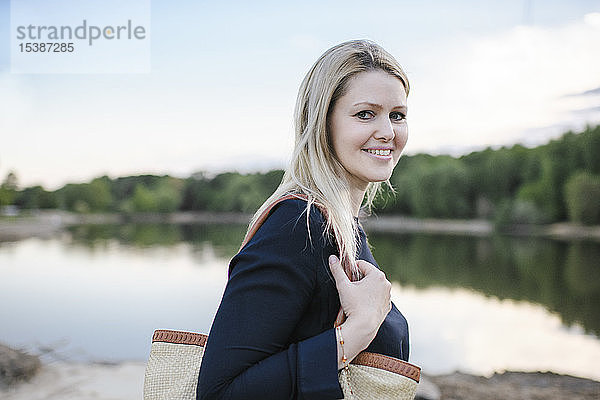 Porträt einer lächelnden blonden Frau an einem See