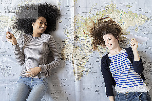 Freunde liegen auf der Karte  werfen mit Papierpalnen  planen ihren Urlaub