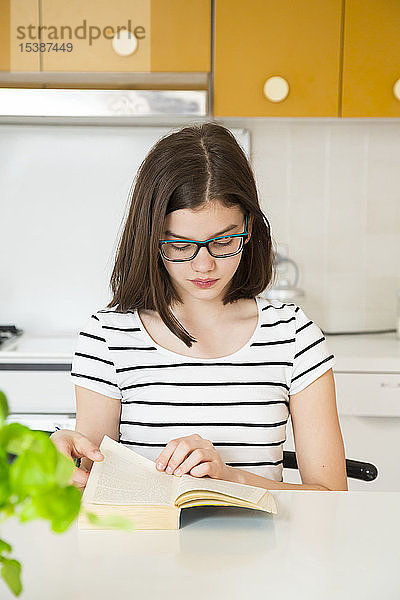 Mädchen liest ein Buch in der Küche