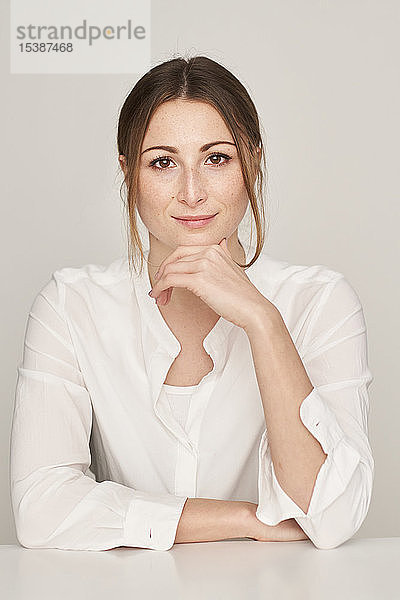 Porträt einer lächelnden jungen Frau in weißer Bluse