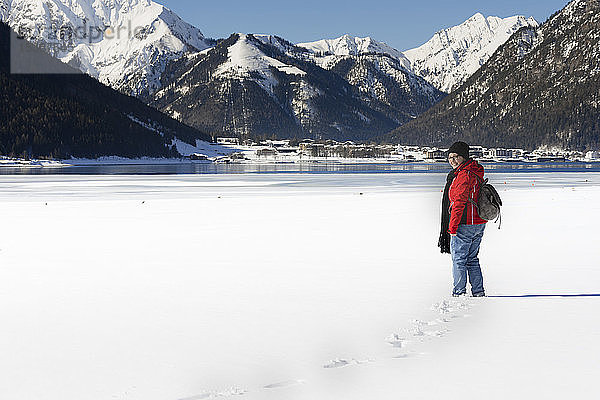 Österreich  Tirol  Achensee  lächelnde Frau  die im Winter am zugefrorenen See steht