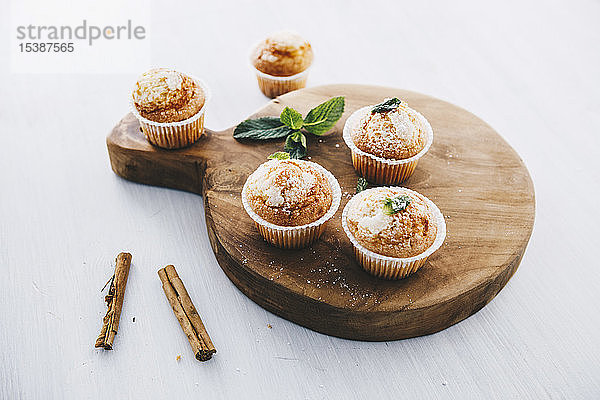 Selbstgebackene Muffins mit Zimt und Minze auf Holzbrettchen