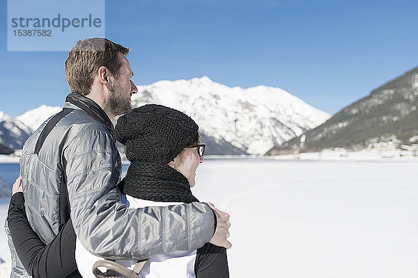 Österreich  Tirol  Achensee  Paar mit Blick auf den zugefrorenen See im Winter