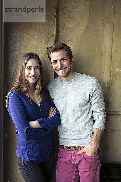 Porträt eines glücklichen jungen Paares  das an einer Wand steht