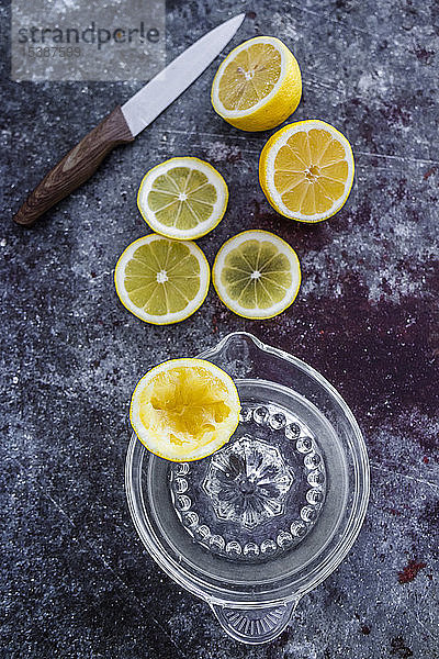 Zitronenhälften und -scheiben und gepresste Zitronenhälfte mit litchen knide und Zitronenpresse