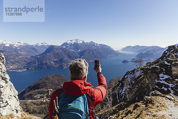 Italien  Como  Mann auf einer Wanderung in den Bergen über dem Comer See beim Fotografieren mit dem Handy