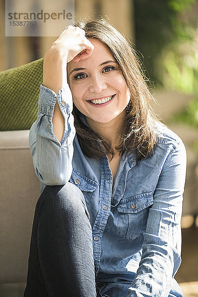 Porträt einer glücklichen Frau  die zu Hause ein Jeanshemd trägt