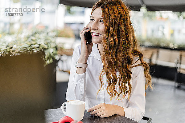 Junge Geschäftsfrau sitzt im Cafe und telefoniert