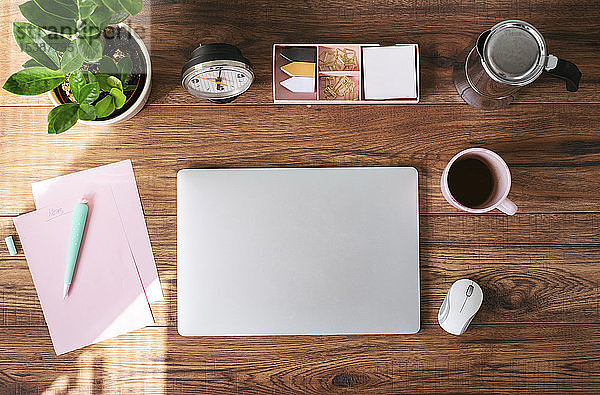 Geschlossener Laptop  Kaffeetasse und andere Utensilien auf dem Schreibtisch im Heimbüro  Draufsicht