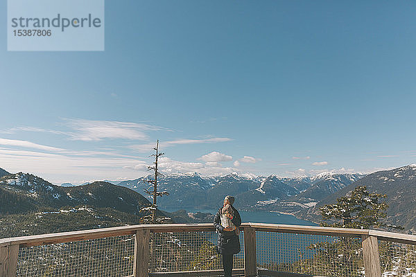 Mutter hält ihren kleinen Sohn auf einer Beobachtungsplattform und schaut über Squamish  Kanada