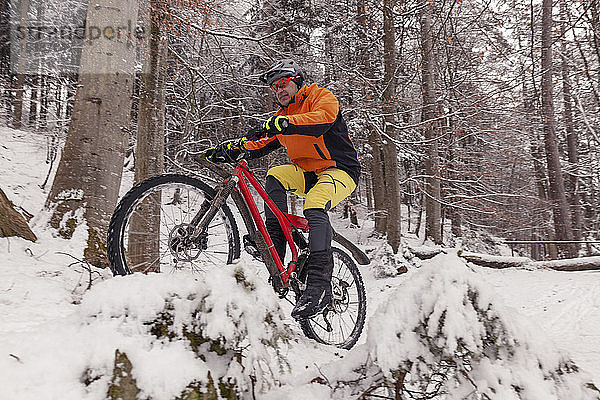 Mann fährt Mountainbike auf Weg im Winterwald