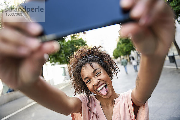 Unbekümmerte junge Frau  die in der Stadt ein Selfie betreibt