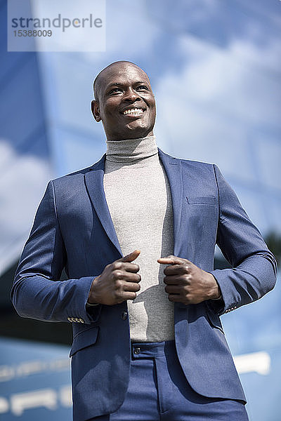Porträt eines zufriedenen Geschäftsmannes in blauem Anzug und grauem Rollkragenpullover