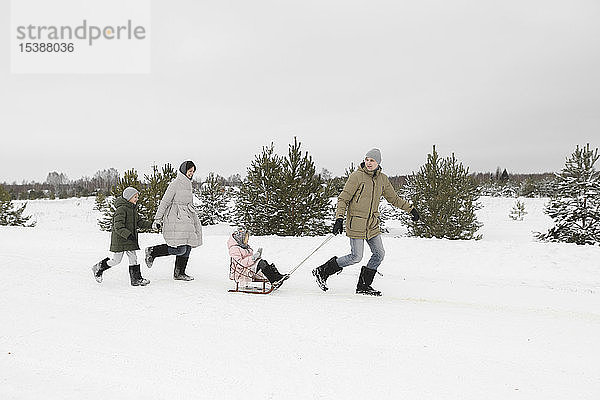Familie amüsiert sich mit Schlitten in schneebedeckter Landschaft