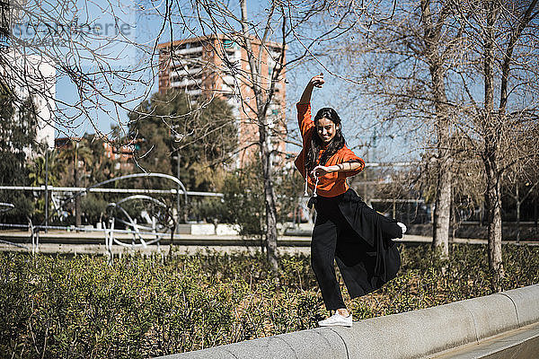 Junge zeitgenössische Tänzerin mit rotem Kapuzen-Shirt  die ihrer Leidenschaft in einem Park nachgeht