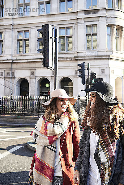 Großbritannien  London  zwei glückliche Frauen in der Stadt beim Überqueren einer Straße