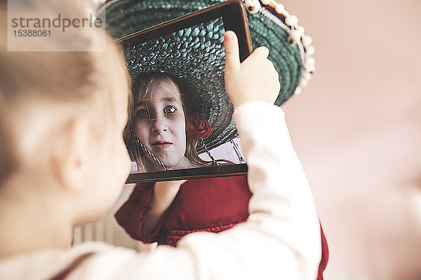 Kleines Mädchen  das eine verkleidete Schwester mit Tablette fotografiert