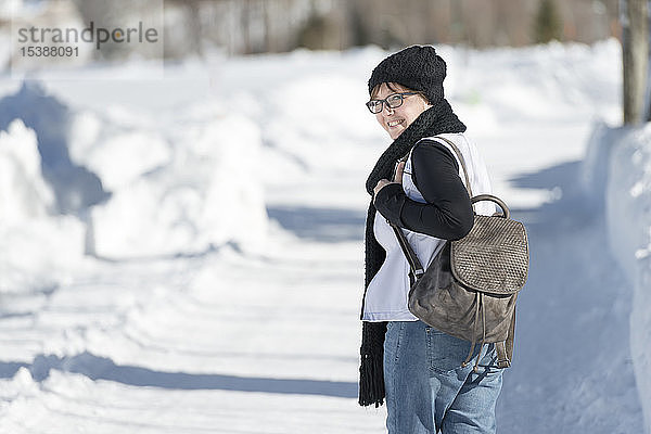 Porträt einer lächelnden Frau mit Rucksack bei einem Winterspaziergang