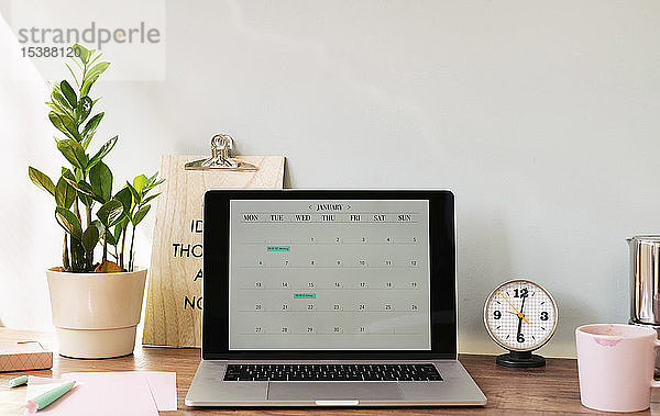 Geöffneter Laptop mit einem Kalender auf dem Schreibtisch im Heimbüro