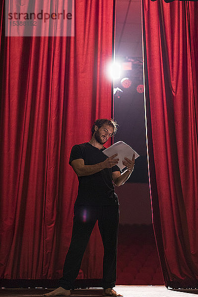 Barfüssiger Schauspieler steht auf der Bühne des Theaters und liest Skript