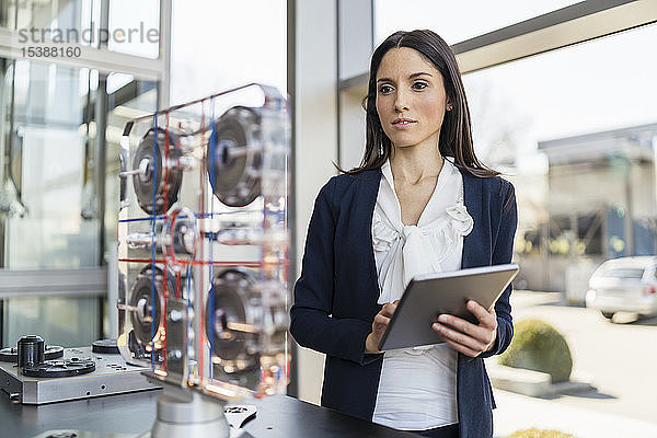 Geschäftsfrau mit Tablette betrachtet Maschine in einer modernen Fabrik
