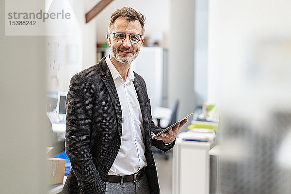 Porträt eines lächelnden Geschäftsmannes mit Tablett im Büro