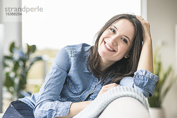 Porträt einer glücklichen Frau  die zu Hause auf der Couch sitzt