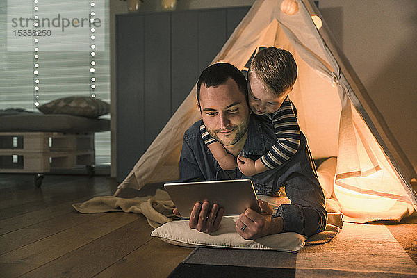 Vater und Sohn teilen sich eine Tafel in einem beleuchteten Zelt zu Hause