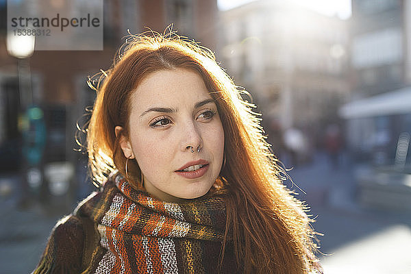 Porträt einer rothaarigen jungen Frau mit Nasenpiercing in der Stadt