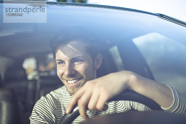 Lächelnder junger Mann beim Autofahren