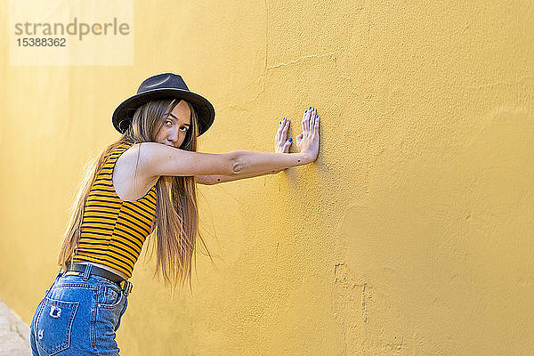 Porträt eines Teenager-Mädchens mit Hut an gelber Wand