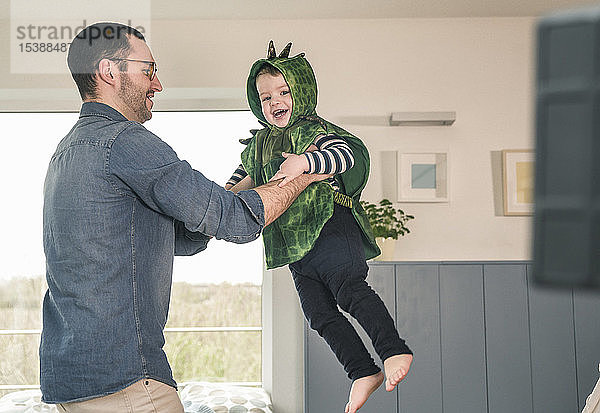 Vater spielt mit glücklichem Sohn im Kostüm zu Hause