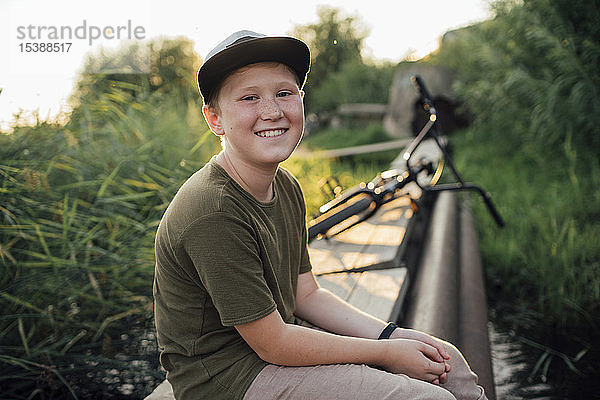 Porträt eines lächelnden Jungen mit bmx-Fahrrad auf der Promenade sitzend