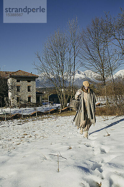 Italien  Limana  Frau mit Korb stolpert durch schneebedeckte Landschaft