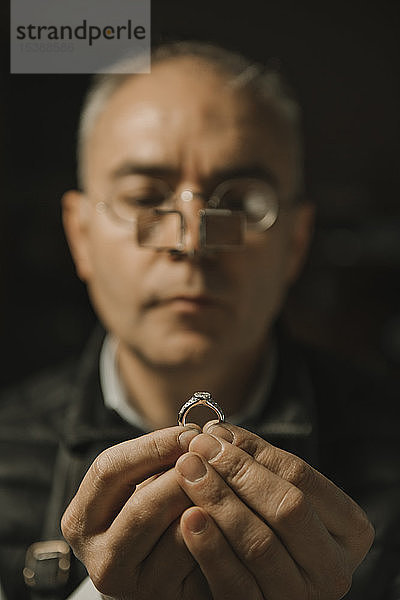 Kunsthandwerker betrachtet Ring mit Edelstein  Porträt